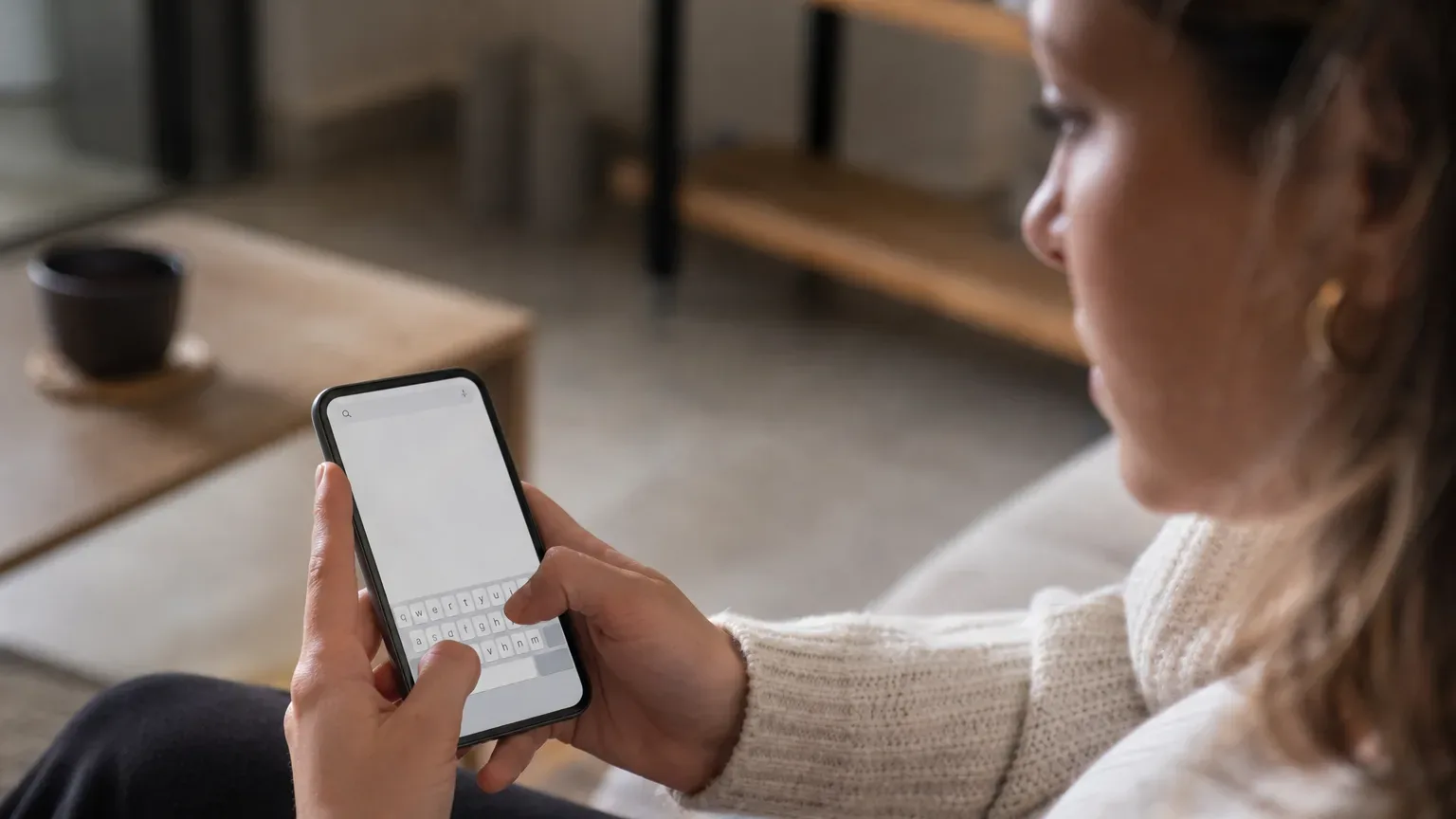 Close-up of hands typing a search query into a smartphone browser