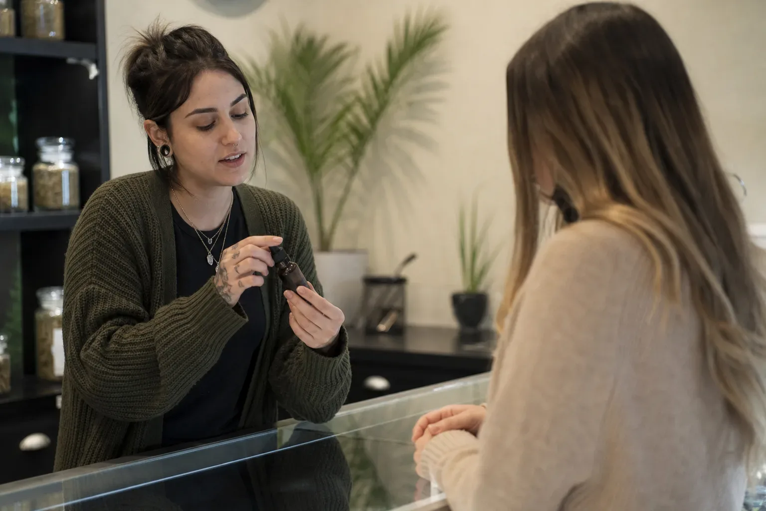A budtender demonstrating the use of a dropper bottle to a patient across a clean dispensary counter