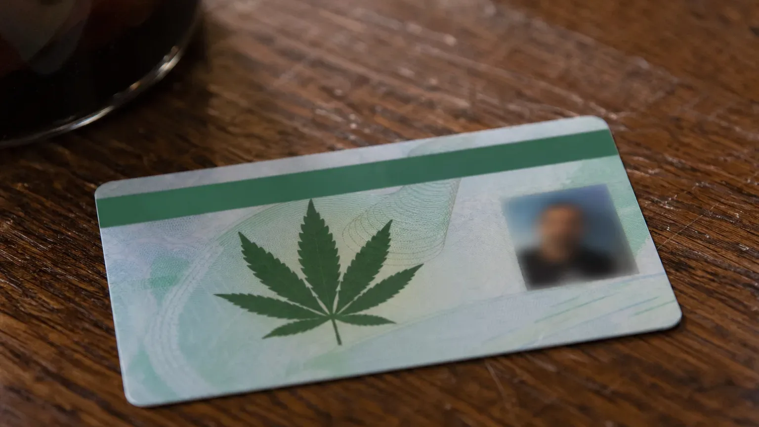 A close-up of a laminated medical marijuana card resting on a wooden tabletop