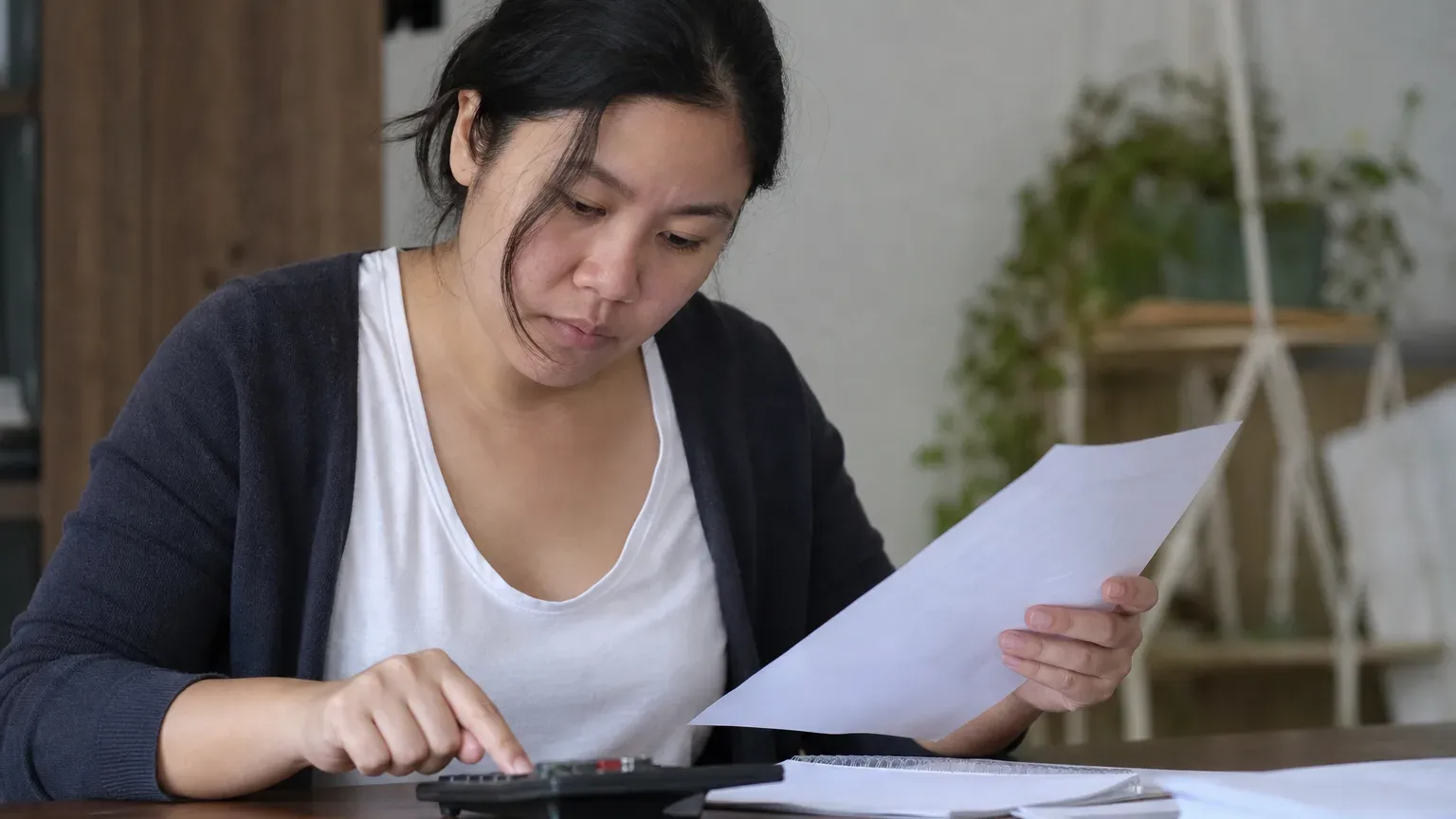 A person comparing the cost of a medical card renewal fee listed on a document against a calculator result