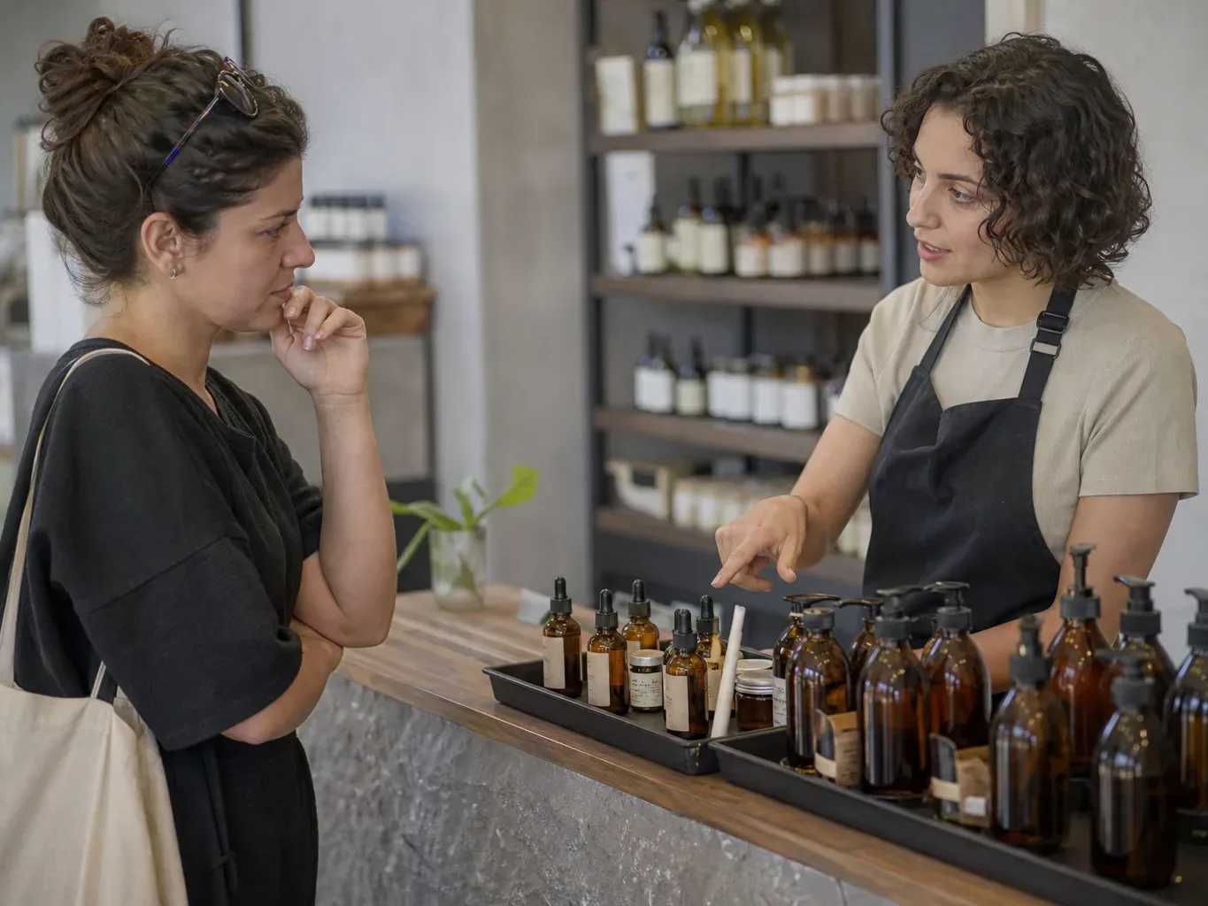 A customer listening attentively while a staff member gestures toward a product tray on the counter